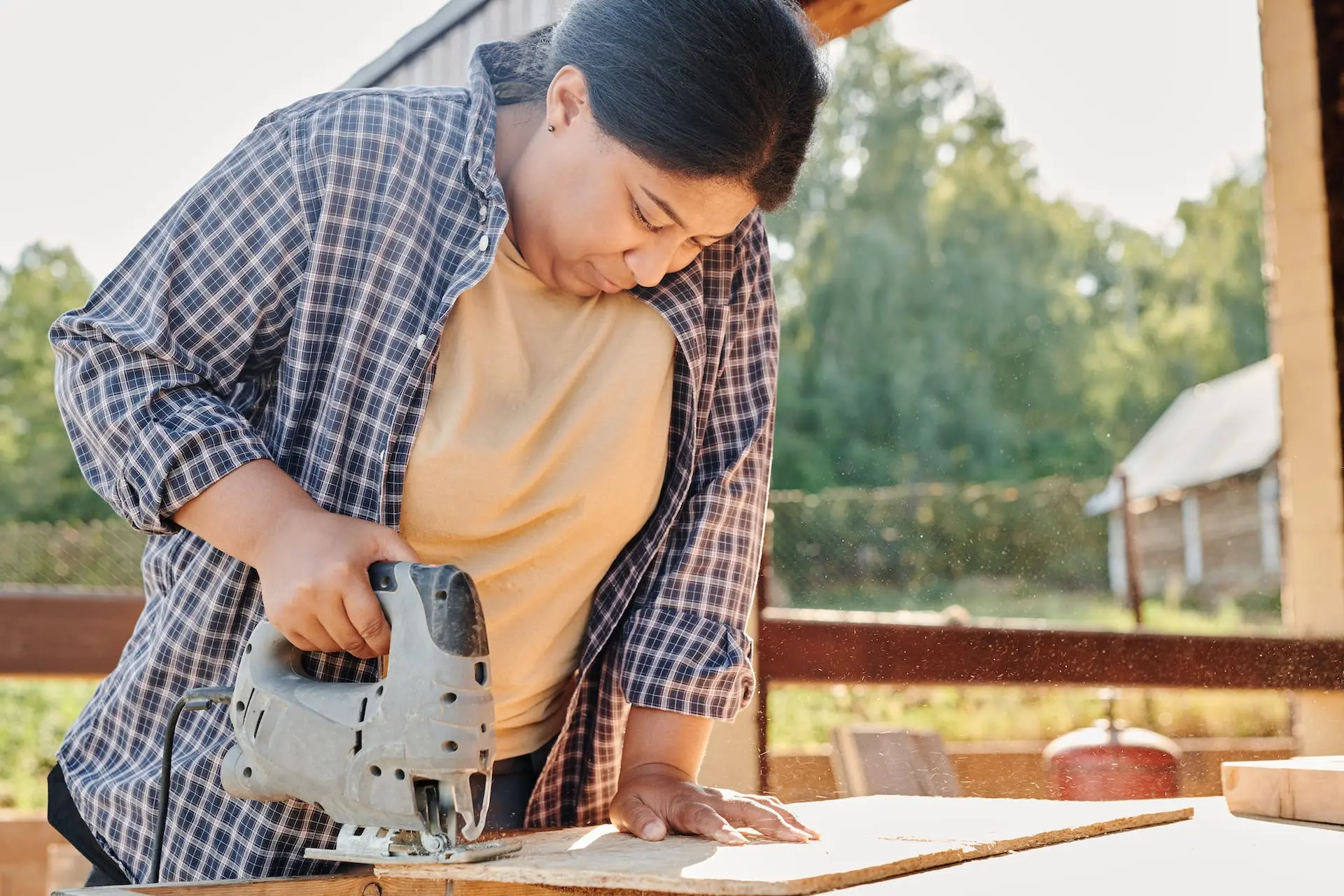 Woman using a jigsaw to cut wood